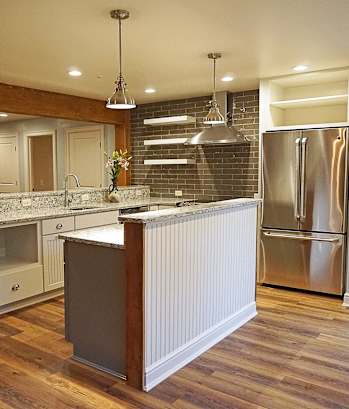 a kitchen with a center island and a stainless steel refrigerator