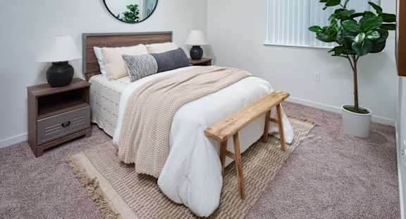 a bedroom with a white bedspread and a round mirror on the wall