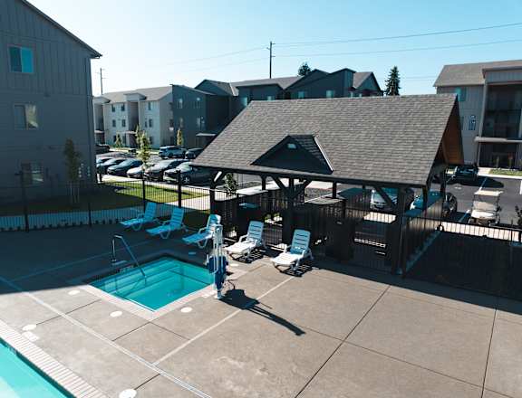 A pool with a pavilion and chairs in front of apartment buildings at Eastpark Apartment Homes, Salem