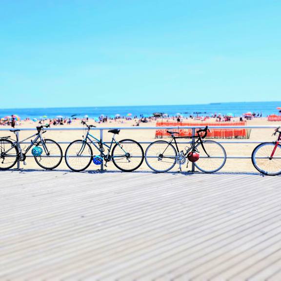 A row of bicycles are parked on a beach.