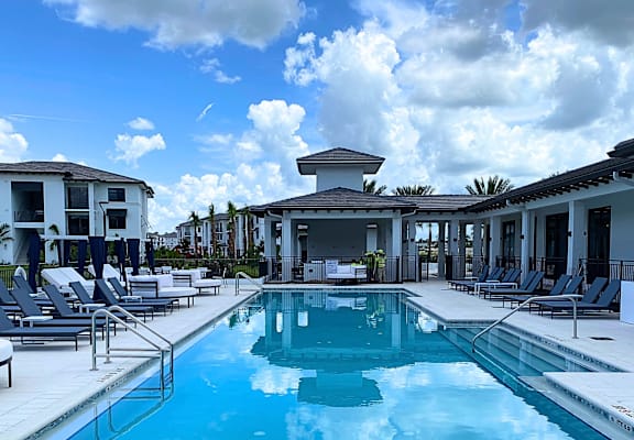 A swimming pool surrounded by lounge chairs and buildings.