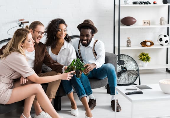 Four people sitting on a couch in a living room.