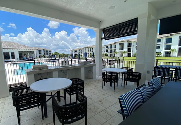 A patio with a table and chairs overlooking a pool.
