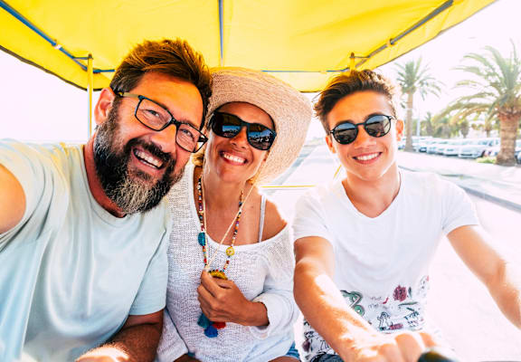 Three people are sitting in a vehicle and taking a selfie.
