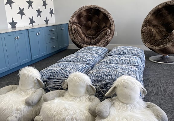 Four stuffed sheep are sitting on the floor.