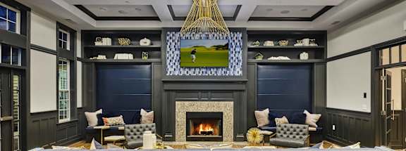 A modern living room with a fireplace and a large grey couch.