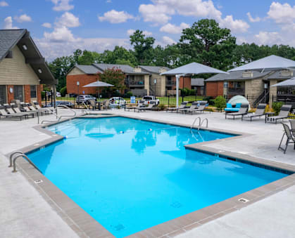A swimming pool surrounded by lounge chairs and umbrellas.