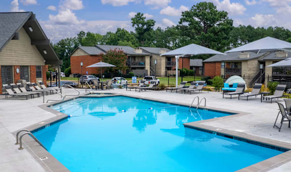 A swimming pool surrounded by lounge chairs and umbrellas.