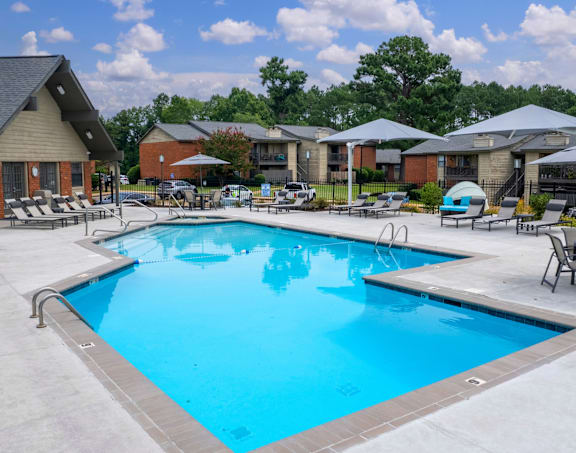 A swimming pool surrounded by lounge chairs and umbrellas.