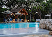 Thumbnail 17 of 48 - Evening pool area with illuminated pavilion and fire feature at Nalle Woods of Westlake Apartments, Austin, TX