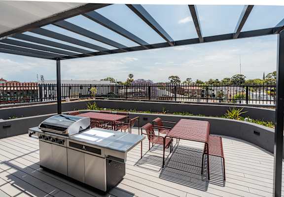 a patio with a barbecue grill and tables and chairs