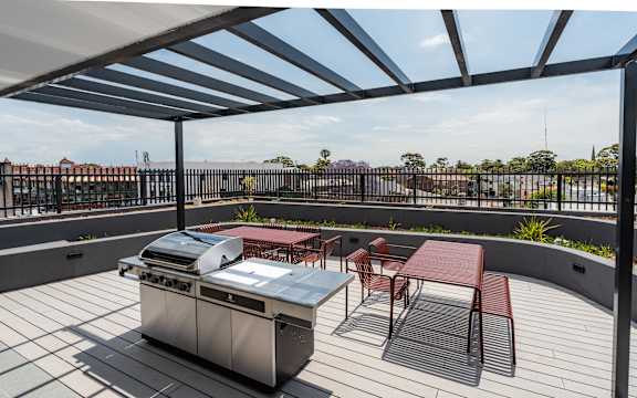 a patio with a barbecue grill and tables and chairs