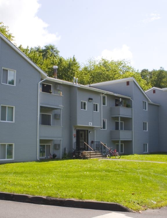 a gray apartment building with a green lawn