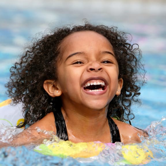 a young girl laughing in a swimming pool
