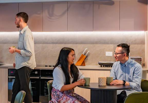 people in a kitchen and dining area with tables and chairs