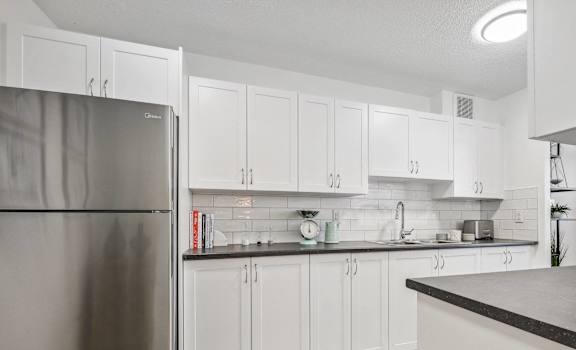 a large kitchen with white cabinets and a stainless steel refrigerator