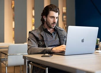 a man sitting at a table using a laptop computer
