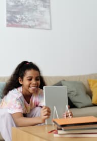 a little girl laying on a couch using a tablet computer at ReVive Apartments, Washington, 98424