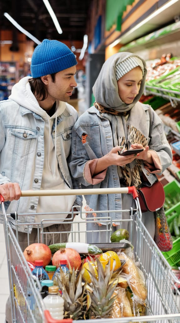 a couple shopping in a grocery store with a shopping cart