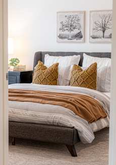 a bedroom with a bed and pillows and pictures on the wall