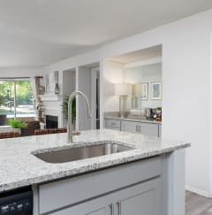 an open kitchen and living room with a sink and counter top