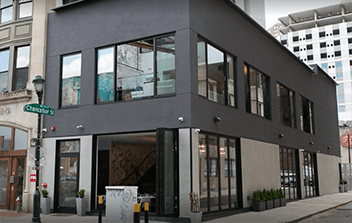 A grey building with a black awning and a green street sign.