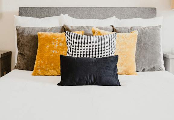 a white bed with pillows and a picture on the wall above it