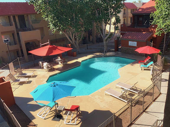 A pool surrounded by chairs and umbrellas.