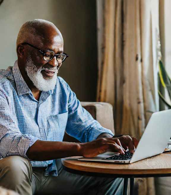 A man is sitting on a couch using a laptop.