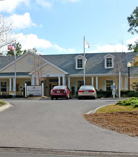 A building with a flag on top and a car parked in front.