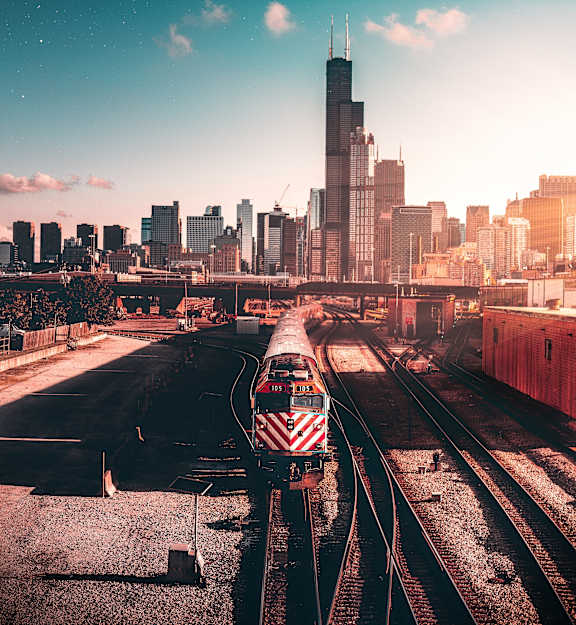 A train is on the tracks in front of a city skyline.