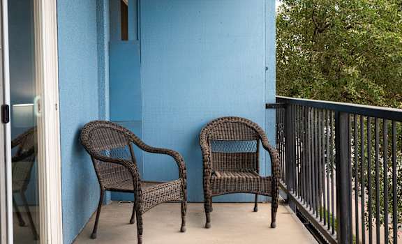 a balcony with two wicker chairs and a blue wall