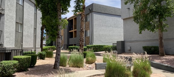 a courtyard with trees and shrubs in front of a building