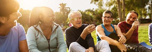 a group of people sitting in a park talking and laughing