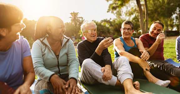 A group of people sitting on a mat in a park.at Union at 16th, Indianapolis Indiana