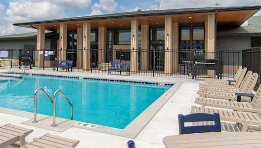 A pool with sun loungers and a building in the background.