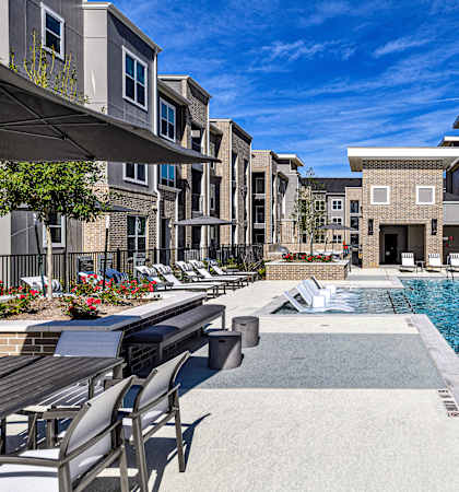 A swimming pool surrounded by lounge chairs and buildings.
