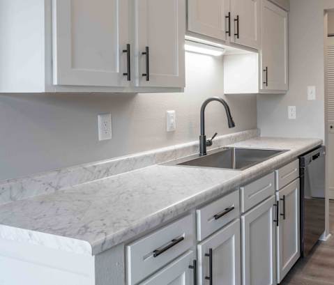 a kitchen with marble counter tops and white cabinets