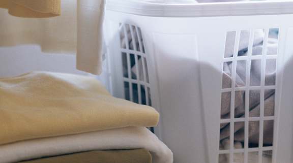 A white laundry basket is full of clothes. at University Landing Apartments, Silver Spring, MD, 20903