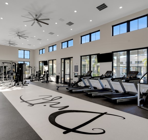 a gym with weights and cardio machines and a large sign on the floor at Drift, Daytona Beach, FL, 32117