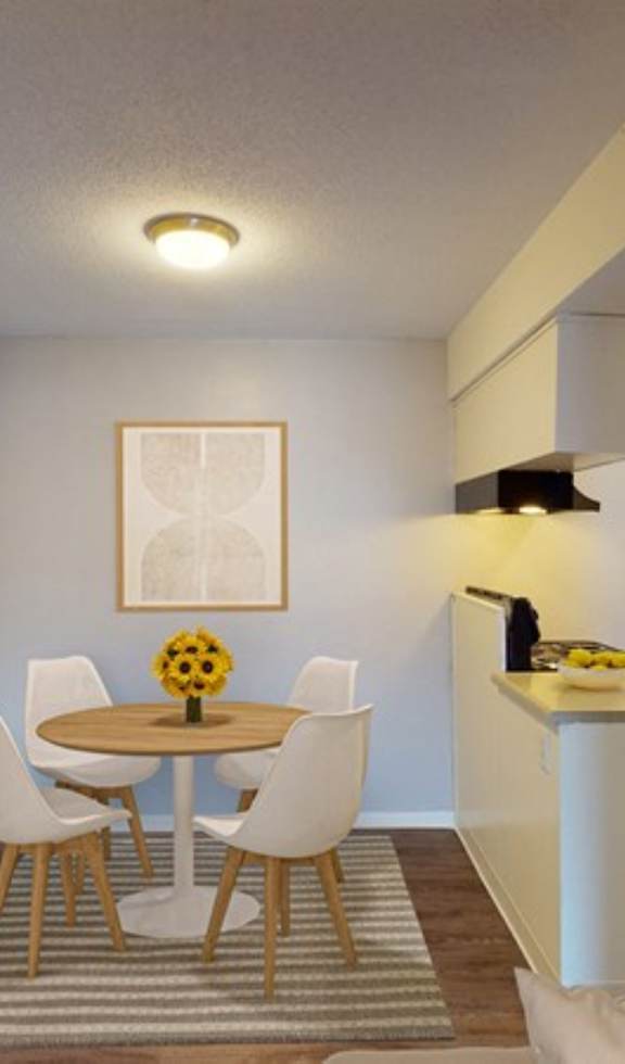 A dining room with a table, chairs, and a vase of sunflowers.