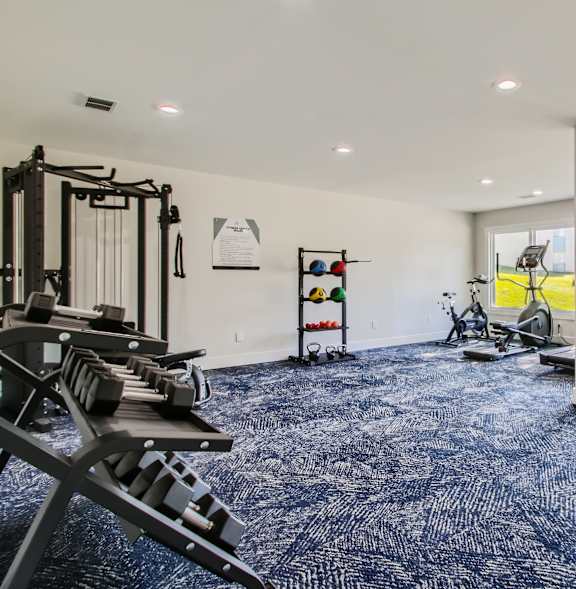 A gym with a variety of equipment including a treadmill, rowing machine, and weights.
