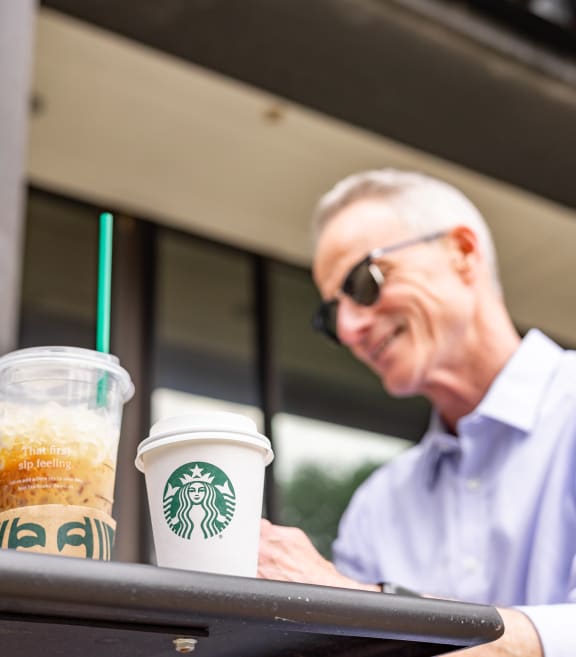 a man sitting at a table with two cups of starbucks coffee at The Washington at Chatham, Pittsburgh, PA 15219