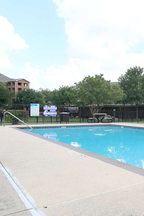 A large swimming pool surrounded by a black fence.