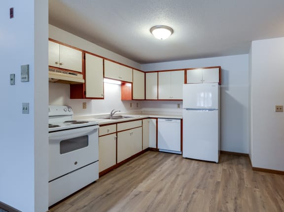 an empty kitchen with white appliances and white cabinets