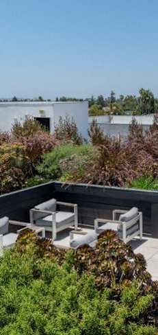 A rooftop patio with a table and chairs overlooks a cityscape.