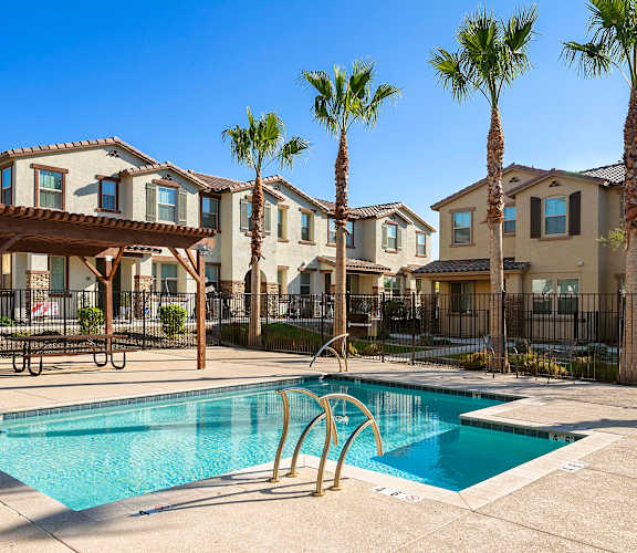 A swimming pool in front of a row of houses with palm trees. at Casa Sole Vita Townhomes, Mesa, 85208