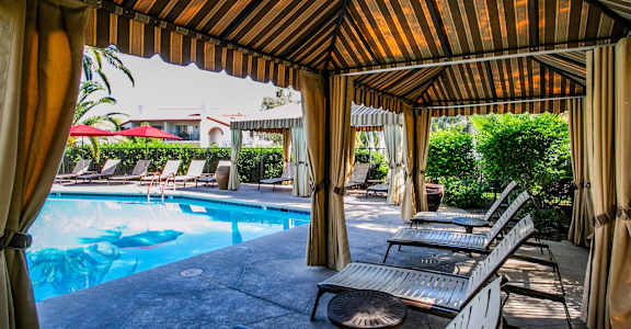 a covered patio with chairs and a swimming pool