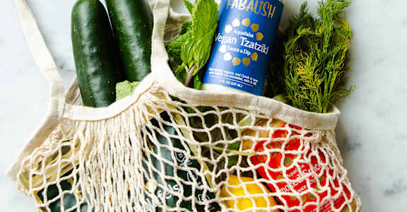 a reusable grocery bag filled with vegetables and a jar of juice