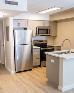 A kitchen with a refrigerator, microwave, oven, and sink.